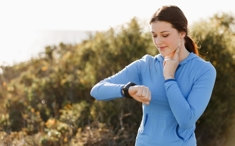 Mulher medindo a frequência cardíaca no treino de corrida